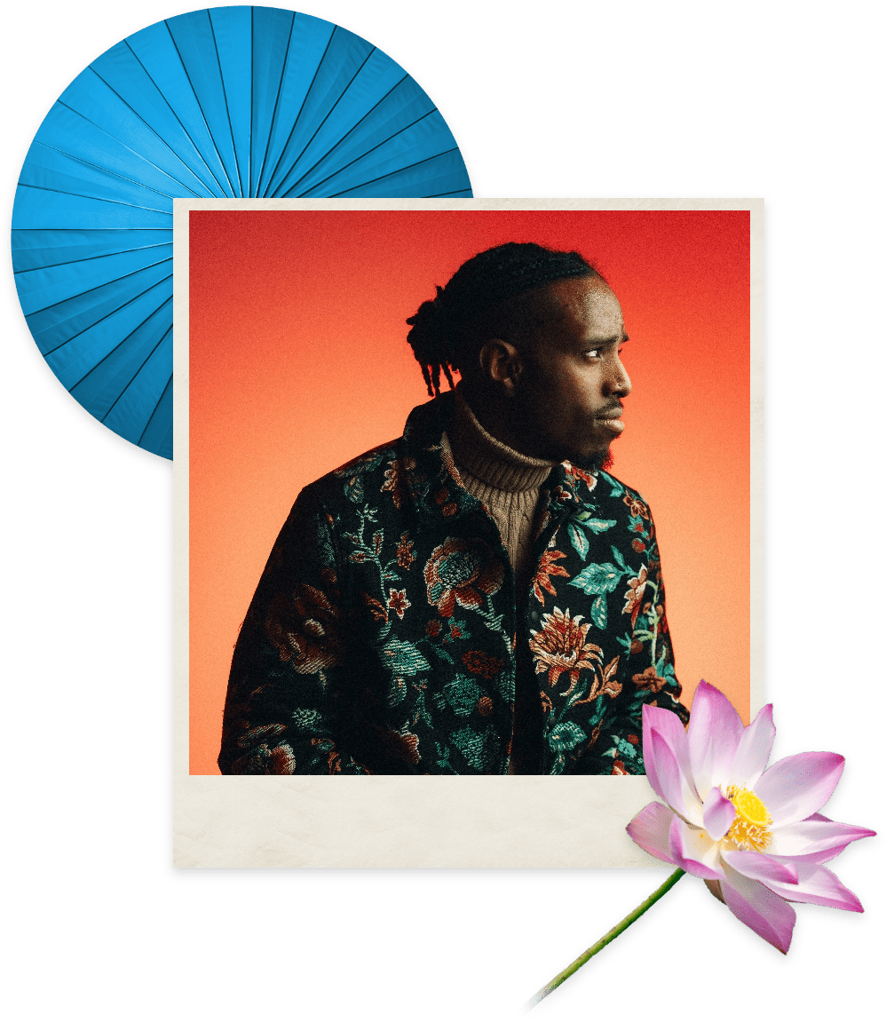 A black man wearing an embroidered jacket with flowers set against an orange background with a blue fan and a white and pink flower in the corners.