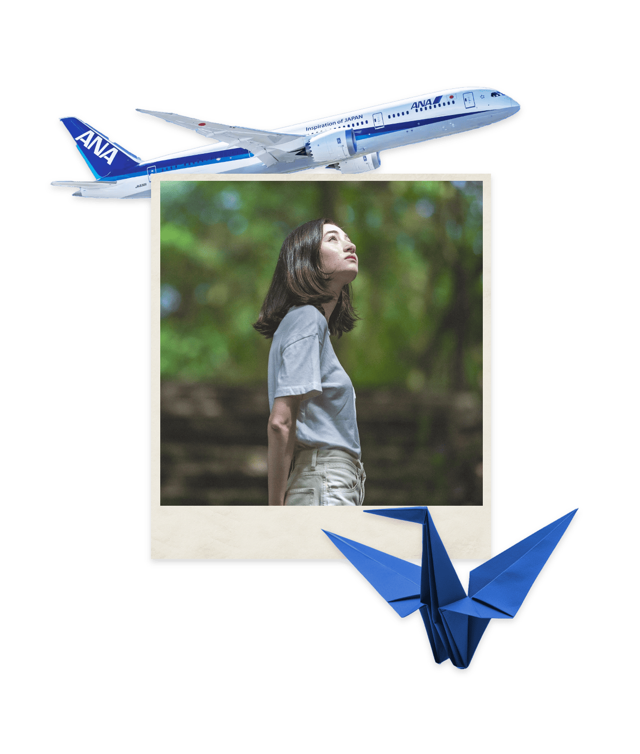 A woman in a white t-shirt gazes up at the sky in a wooded area with a blue origami crane and an ANA airplane in opposite corners.