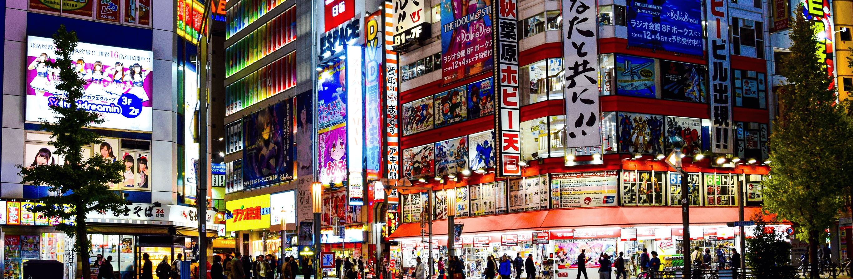 A bustling street scene at night in an urban area with bright neon signs and advertisements, crowded with pedestrians traveling across Japan.